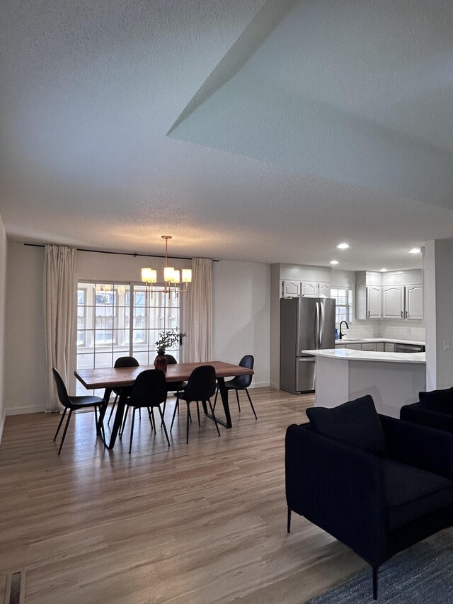 dining room with plenty of natural light, visible vents, light wood-type flooring, and an inviting chandelier