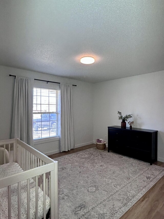 bedroom featuring wood finished floors, baseboards, and a textured ceiling