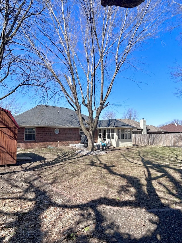 rear view of property featuring brick siding and fence