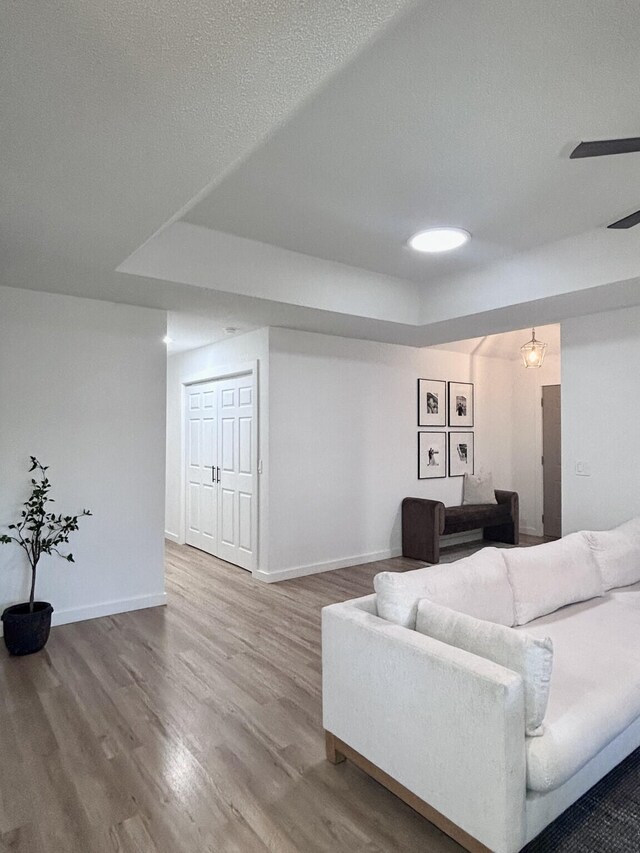 living room featuring a textured ceiling, baseboards, and wood finished floors