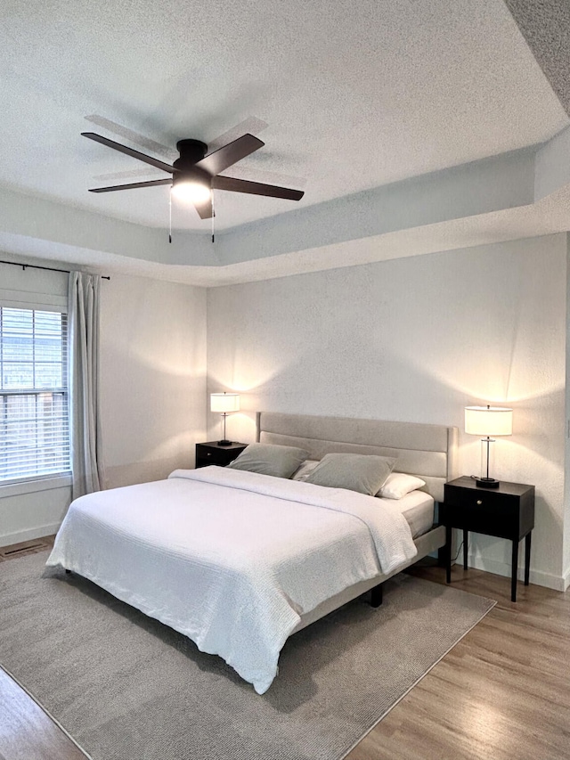 bedroom featuring visible vents, a ceiling fan, a textured ceiling, wood finished floors, and baseboards