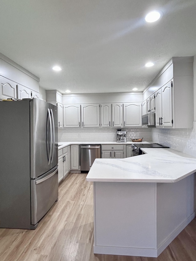 kitchen with decorative backsplash, recessed lighting, light wood-style flooring, a peninsula, and stainless steel appliances