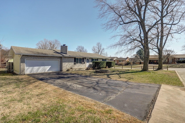 ranch-style house with a front lawn, fence, a chimney, driveway, and an attached garage