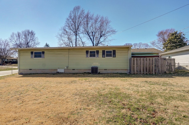 rear view of house with fence, a lawn, and crawl space