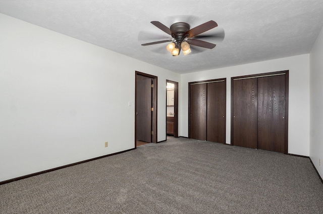 unfurnished bedroom featuring multiple closets, a ceiling fan, a textured ceiling, carpet, and baseboards