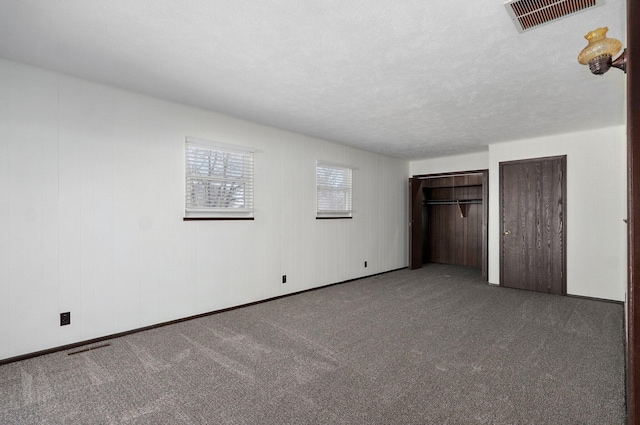 unfurnished bedroom with a textured ceiling, visible vents, two closets, and carpet floors