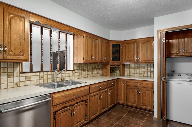 kitchen featuring dishwasher, washer / dryer, brown cabinets, and a sink