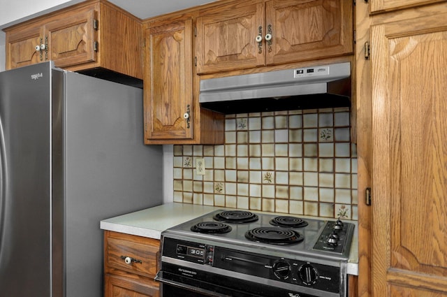 kitchen featuring range with electric cooktop, under cabinet range hood, tasteful backsplash, freestanding refrigerator, and light countertops