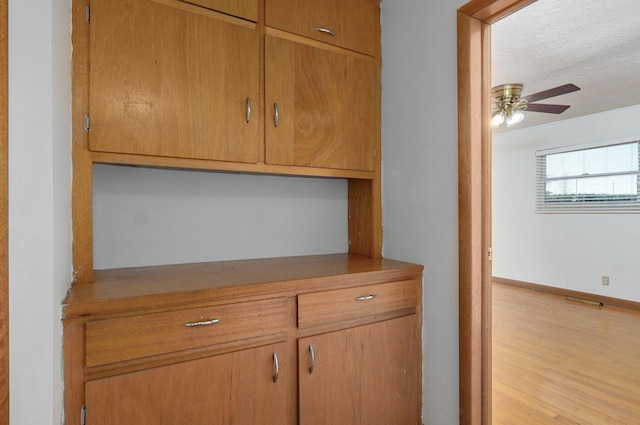 room details featuring baseboards, a textured ceiling, wood finished floors, and a ceiling fan