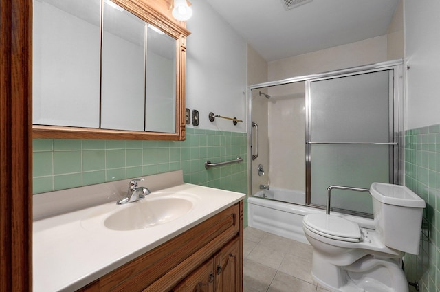 full bath with toilet, shower / bath combination with glass door, tile walls, tile patterned flooring, and vanity