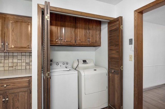 laundry area with washer and clothes dryer, cabinet space, and wood finished floors