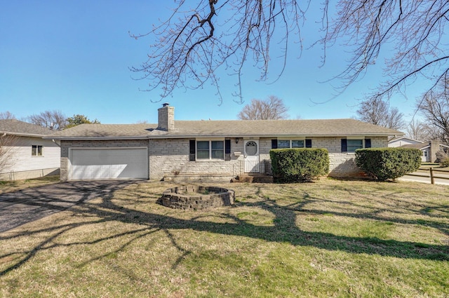 view of front facade with aphalt driveway, a front yard, a garage, brick siding, and a chimney