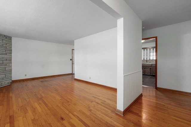 unfurnished room with a sink, baseboards, and light wood-style flooring