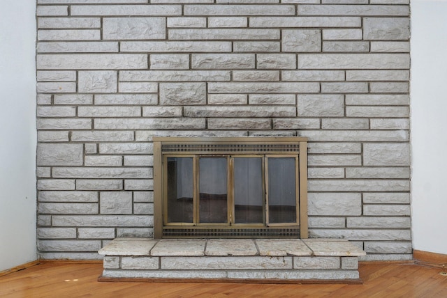 room details with a brick fireplace, baseboards, and wood finished floors