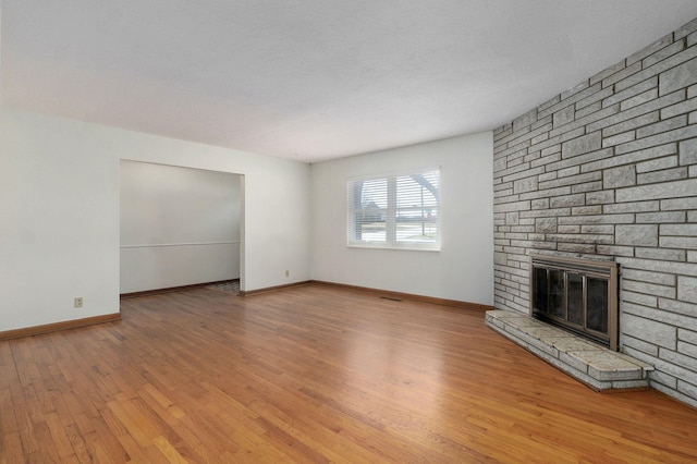 unfurnished living room with a fireplace, baseboards, and wood finished floors