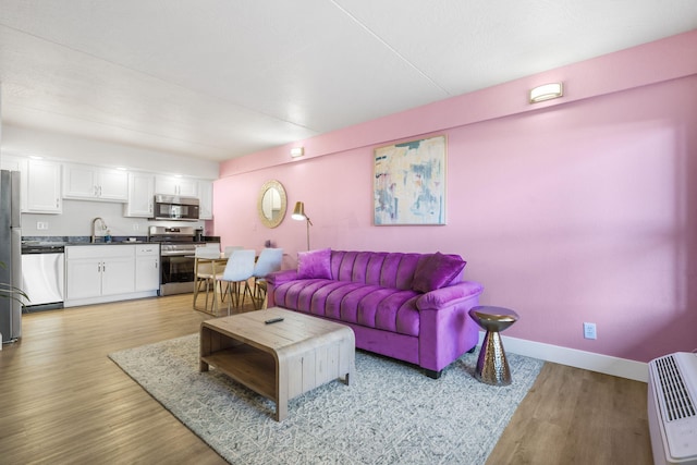 living area with light wood finished floors, heating unit, and baseboards
