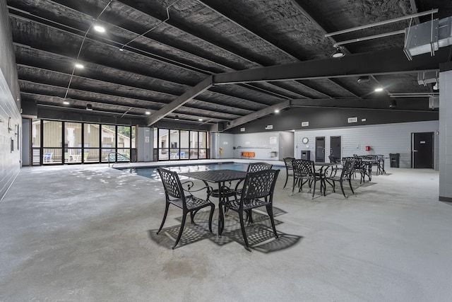 dining room featuring lofted ceiling with beams and unfinished concrete floors