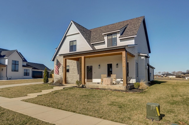 view of front of property featuring covered porch, roof with shingles, and a front yard