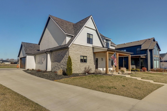 view of front of property featuring stone siding, covered porch, concrete driveway, and a front yard