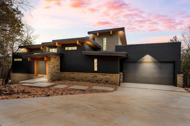 view of front of house featuring stone siding, driveway, and an attached garage