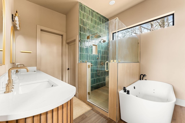 full bath featuring a soaking tub, a shower stall, wood finished floors, and a sink