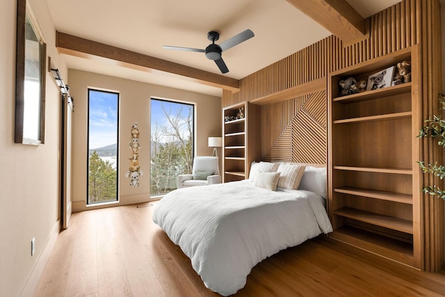 bedroom with baseboards, beam ceiling, wood finished floors, and a ceiling fan