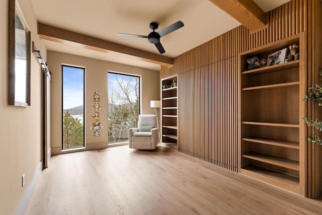 unfurnished room featuring beam ceiling, a ceiling fan, and wood finished floors