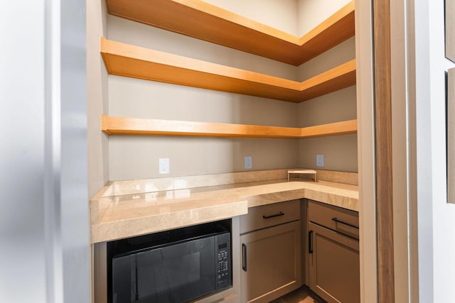 kitchen with open shelves, black microwave, and light countertops