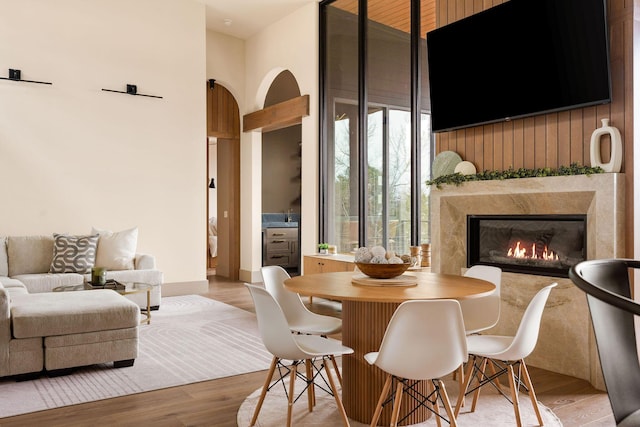 dining area featuring a fireplace, a towering ceiling, and wood finished floors