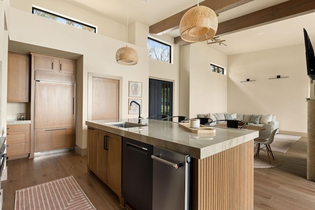 kitchen featuring a sink, beamed ceiling, an island with sink, and wood finished floors