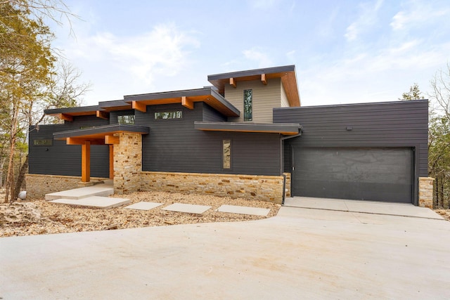 contemporary home featuring a garage, stone siding, and driveway