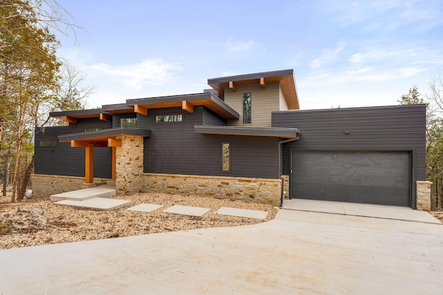 modern home featuring stone siding, an attached garage, and driveway