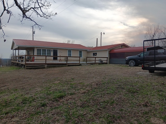 view of front of property with a deck, a front yard, and metal roof