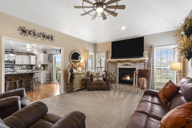 living area with plenty of natural light, light colored carpet, a fireplace, and ceiling fan