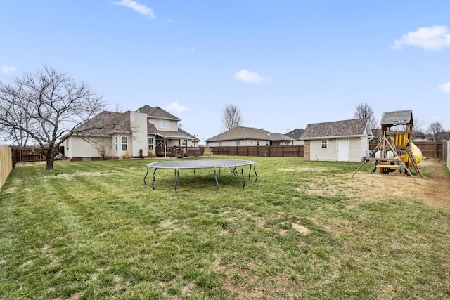 view of yard featuring a fenced backyard, an outbuilding, a playground, and a trampoline