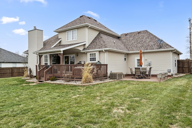 rear view of property featuring a patio area, a lawn, a shingled roof, and fence