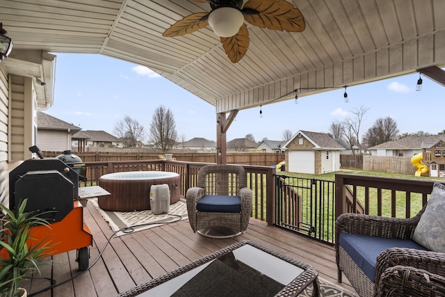 deck featuring an outbuilding, a ceiling fan, a hot tub, a storage unit, and a residential view