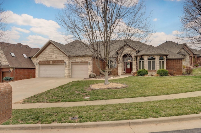 french country style house with driveway, a front lawn, an attached garage, a shingled roof, and brick siding