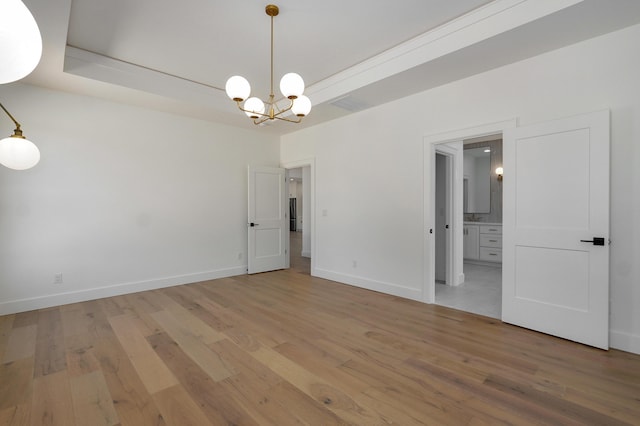 unfurnished room featuring an inviting chandelier, baseboards, and light wood finished floors