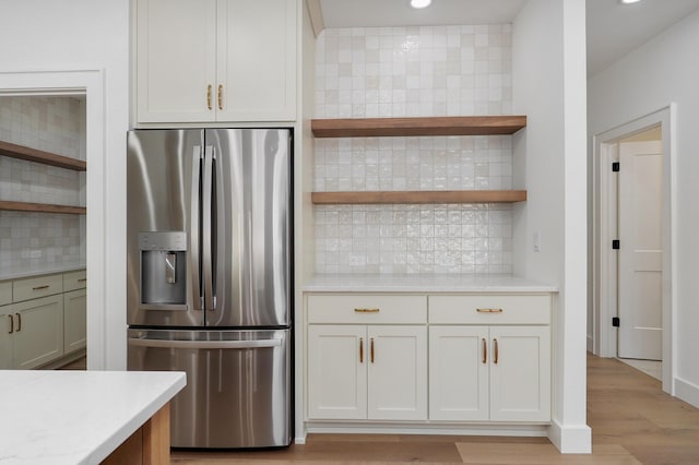 kitchen featuring light countertops, stainless steel refrigerator with ice dispenser, and open shelves