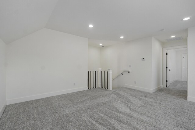 empty room featuring visible vents, lofted ceiling, recessed lighting, carpet flooring, and baseboards