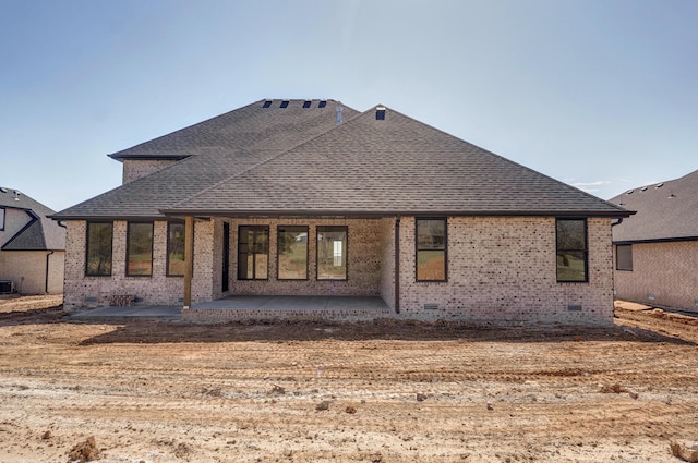 rear view of house featuring brick siding, a patio area, roof with shingles, cooling unit, and crawl space