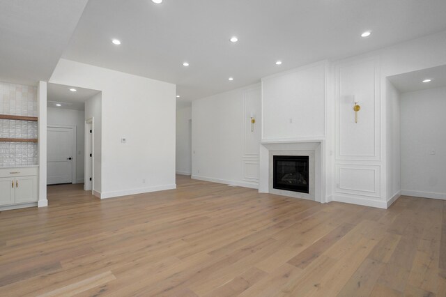 unfurnished living room with recessed lighting, baseboards, light wood-style flooring, and a fireplace