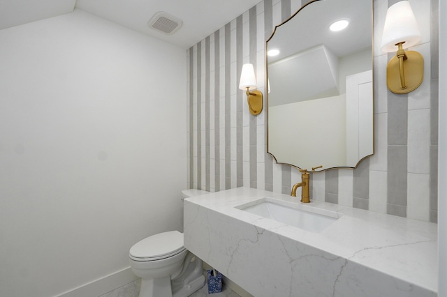 bathroom featuring toilet, visible vents, baseboards, and a sink