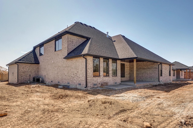 back of house featuring central AC unit, a shingled roof, crawl space, a patio area, and brick siding