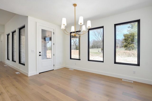 entrance foyer with visible vents, light wood-style flooring, an inviting chandelier, and baseboards