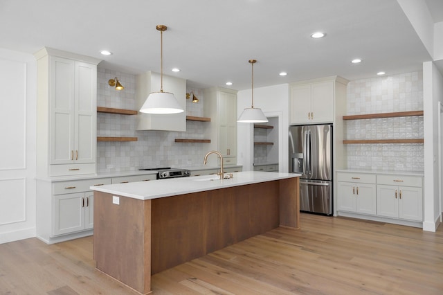 kitchen with open shelves, light wood-type flooring, light countertops, appliances with stainless steel finishes, and a sink