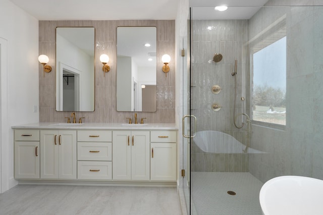 full bath with double vanity, a stall shower, tile walls, and a sink