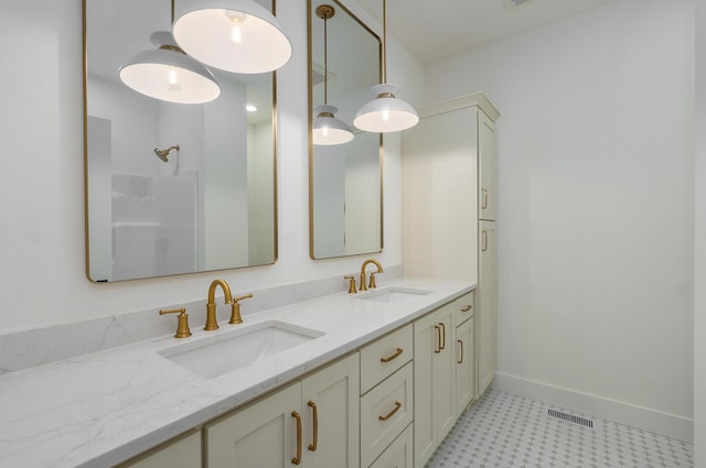 bathroom with double vanity, visible vents, baseboards, and a sink