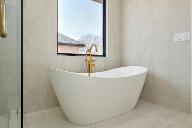 full bath with tile walls and a freestanding bath